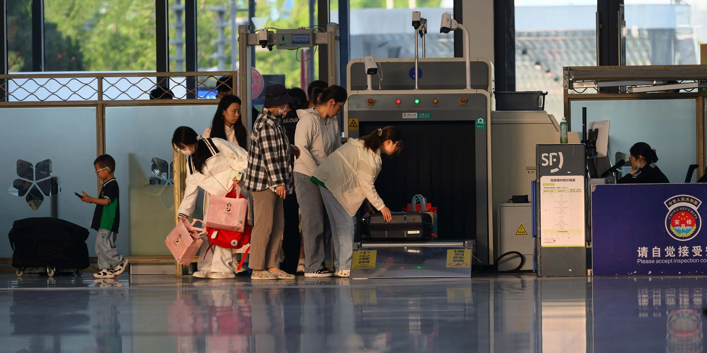Passageiros na fila da segurança de um aeroporto, colocando as bagagens no scanner de raio-X