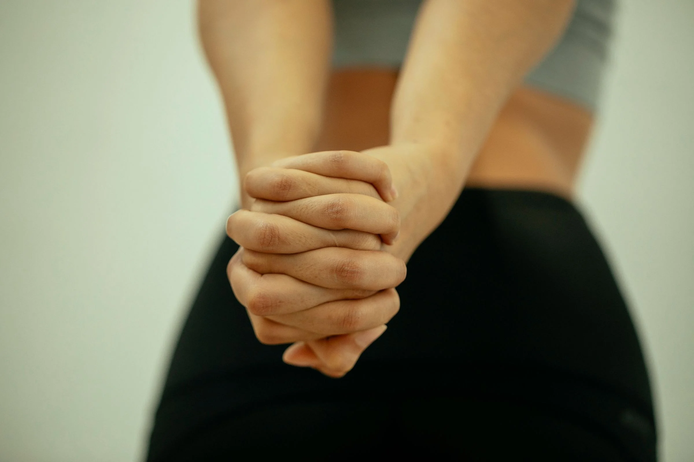 Mãos de um adulto com os dedos entrelaçados, no gesto de quem vai estalar as articulações